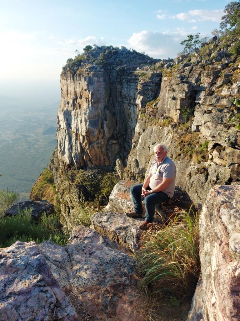 mężczyzna siedzący na skałkach na tle górskiego krajobrazu
