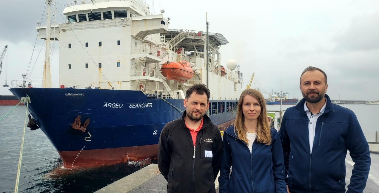 Przedstawiciele PIG-PIB (od lewej) Łukasz Smajdor, Agata Kozłowska-Roman i Michał Tomczak. W tle jednostka r/v Argeo Searcher która stanowiła platformę do obsługi AUV prowadzących akwizycję danych dla PIG-PIB