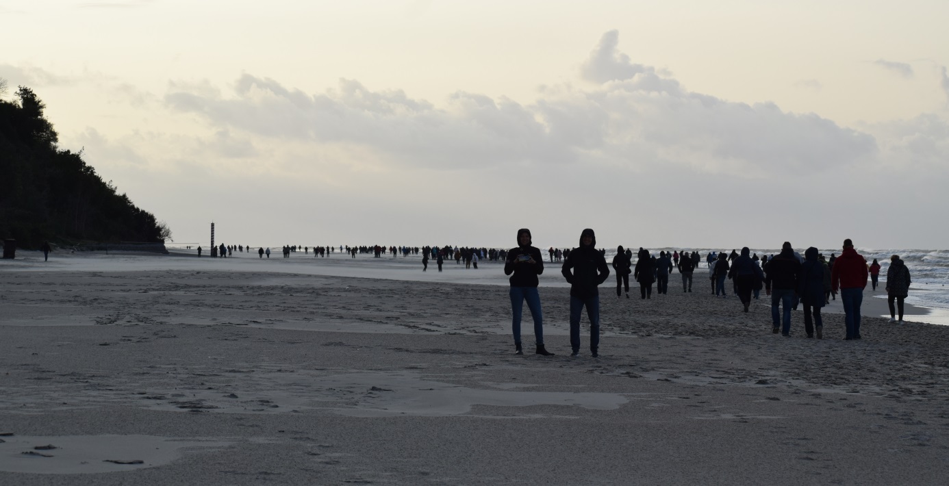 grupa osób przemieszczających się po plaży podczas sztormowej pogody