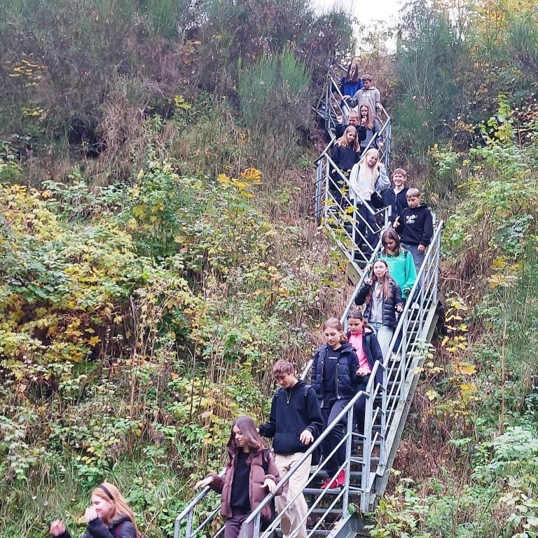 grupa osób schodząca w terenie po wąskich, stromych schodach