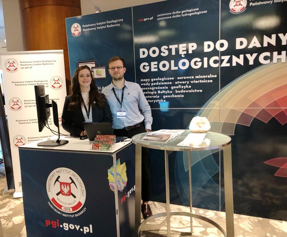 dwie osoby pozują na tle stoiska promocyjnego