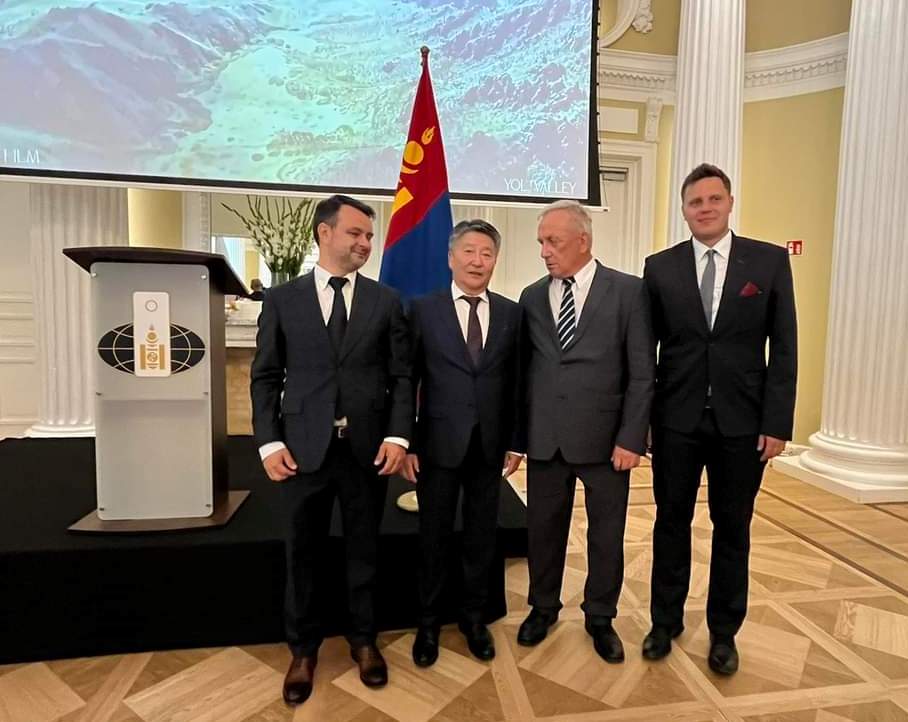 czterech mężczyzn w garniturach pozuje do zdjęcia w eleganckim pomieszczeniu