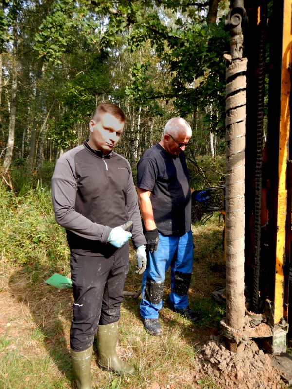 dwóch mężczyzn podczas prac terenowych w terenie zalesionym