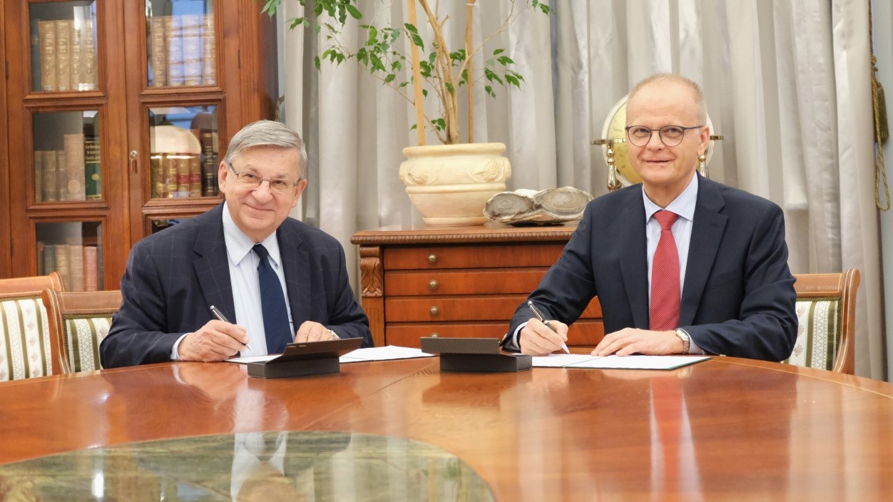 Dwóch mężczyzn siedzi za stołem i podpisuje umowę