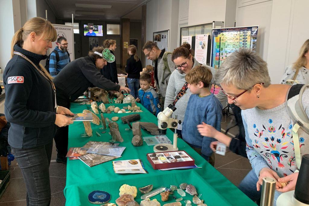 Stoisko na festynie popularnonaukowym, dużo ludzi ogląda okazy geologiczne