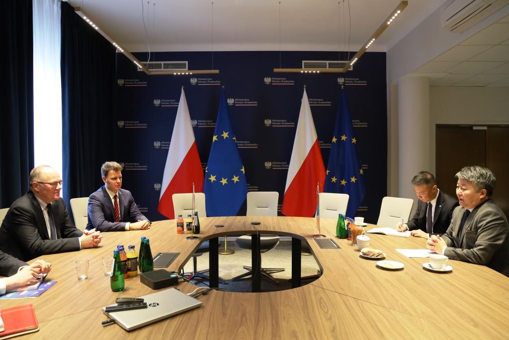 czterej mężczyźni siedzą przy stole w pokoju konferencyjnym z flagami Polski i Mongolii