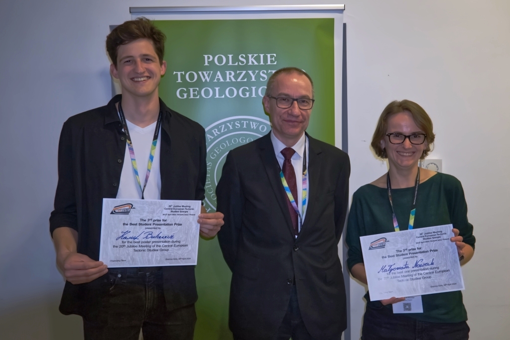 trzy osoby pozują do zdjęcia, dwie z nich trzymają w ręku dyplomy z wyróżnieniem
