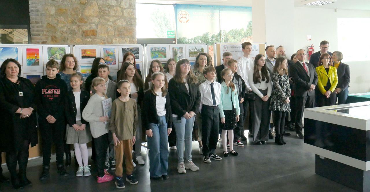grupa dorosłych i dzieci pozuje do zdjęcia w sali muzealnej