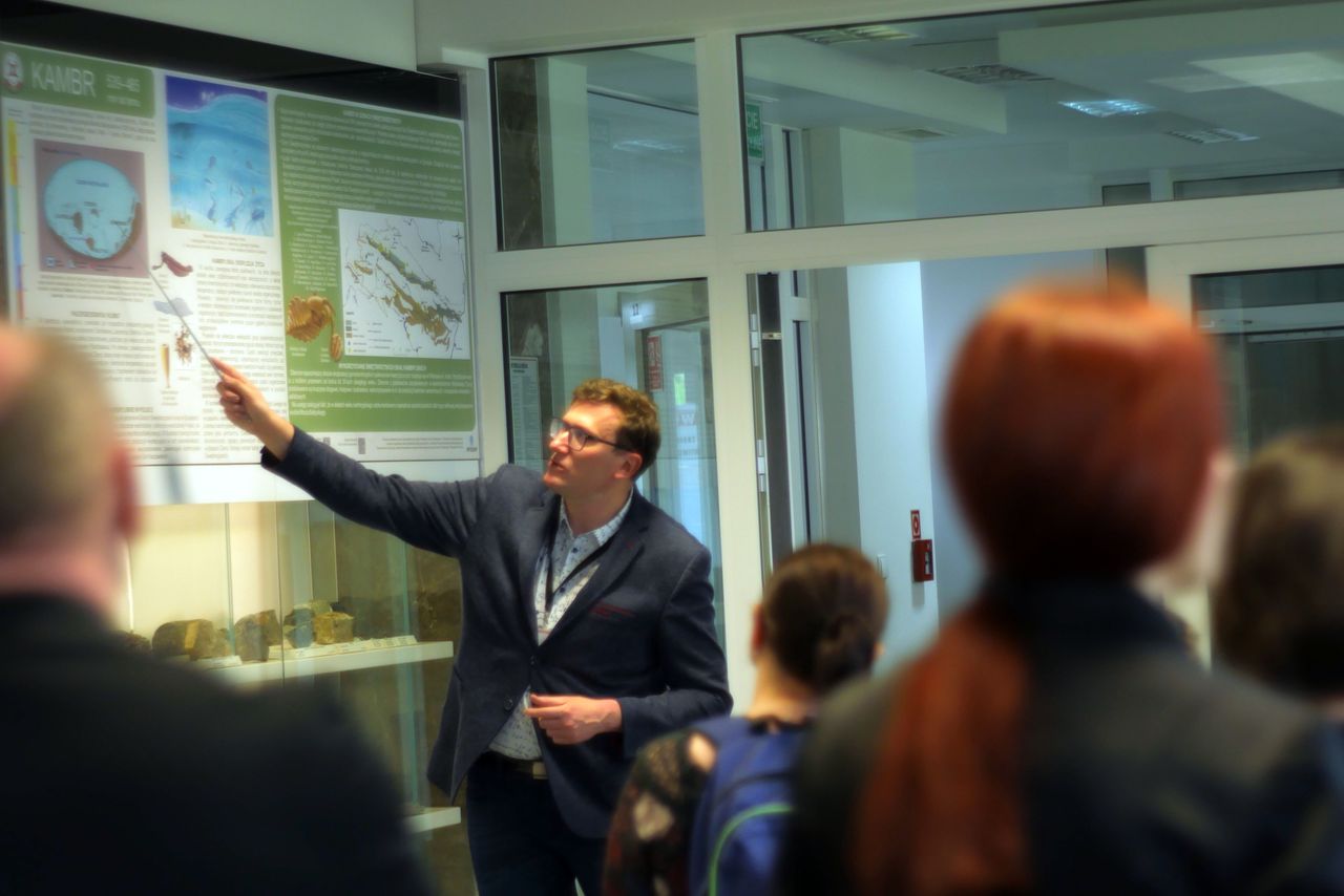 mężczyzna oprowadza uczestników po wystawie w muzeum geologicznym