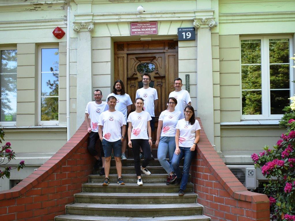 grupa ludzi w strojach sportowych pozujących do zdjęcia na schodach na zewnątrz budynku
