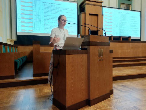 kobieta na mównicy przedstawia referat na tle ekranu z prezentacją