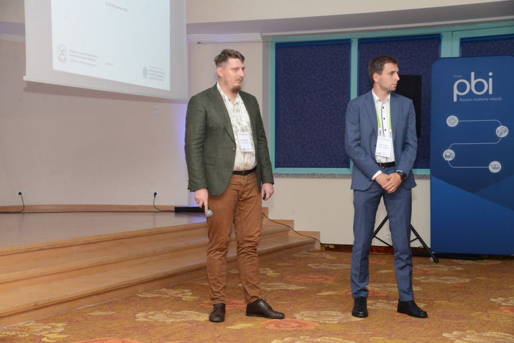 dwóch mężczyzn wygłaszających prezentację na tle ekranu
