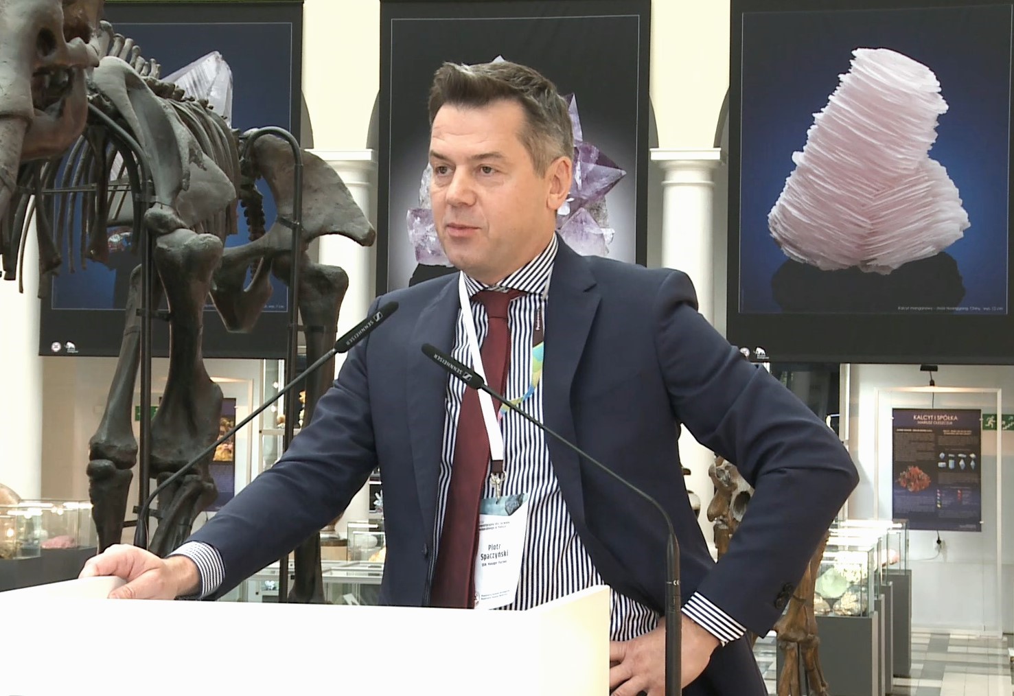 mężczyzna przemawia do siedzącej w pomieszczeniu publiczności
