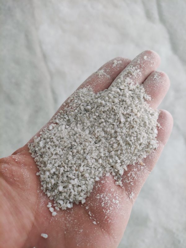 biały sproszkowany surowiec mineralny na dłoni