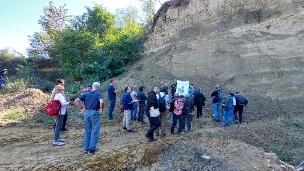 grupa osób oglądających stanowisko geologiczne, skarpę w terenie