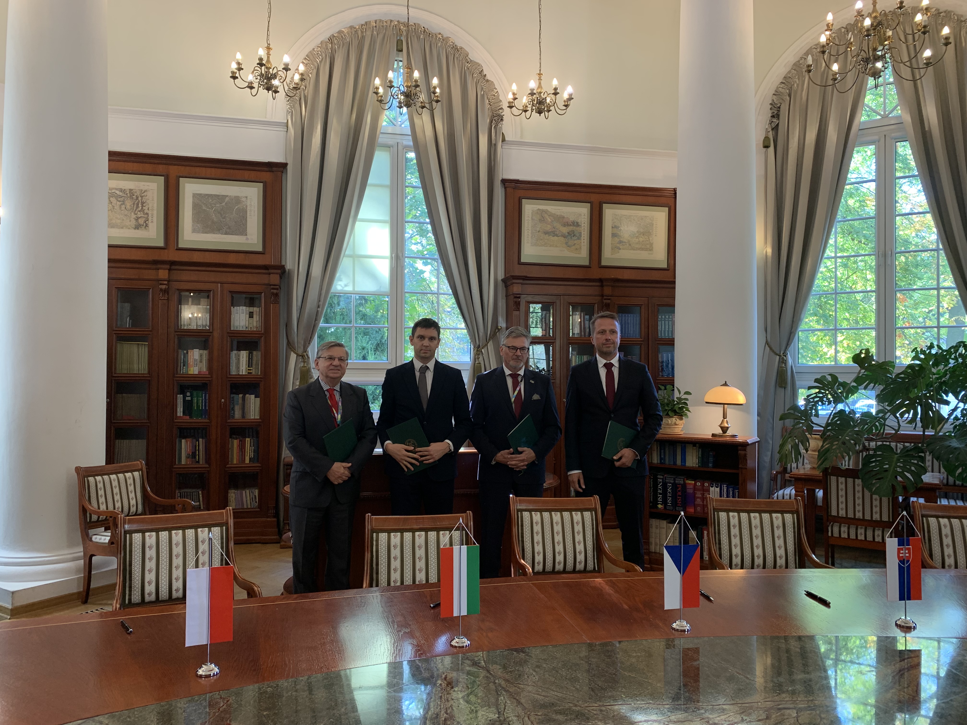 czterech mężczyzn w garniturach pozuje do zdjęcia w eleganckim pomieszczeniu