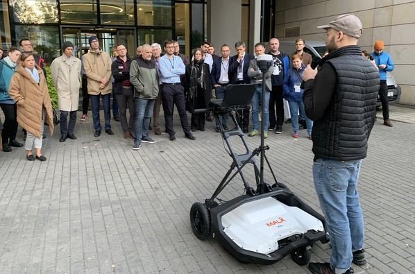 mężczyzna prezentuje nowoczesne urządzenie przed grupą osób