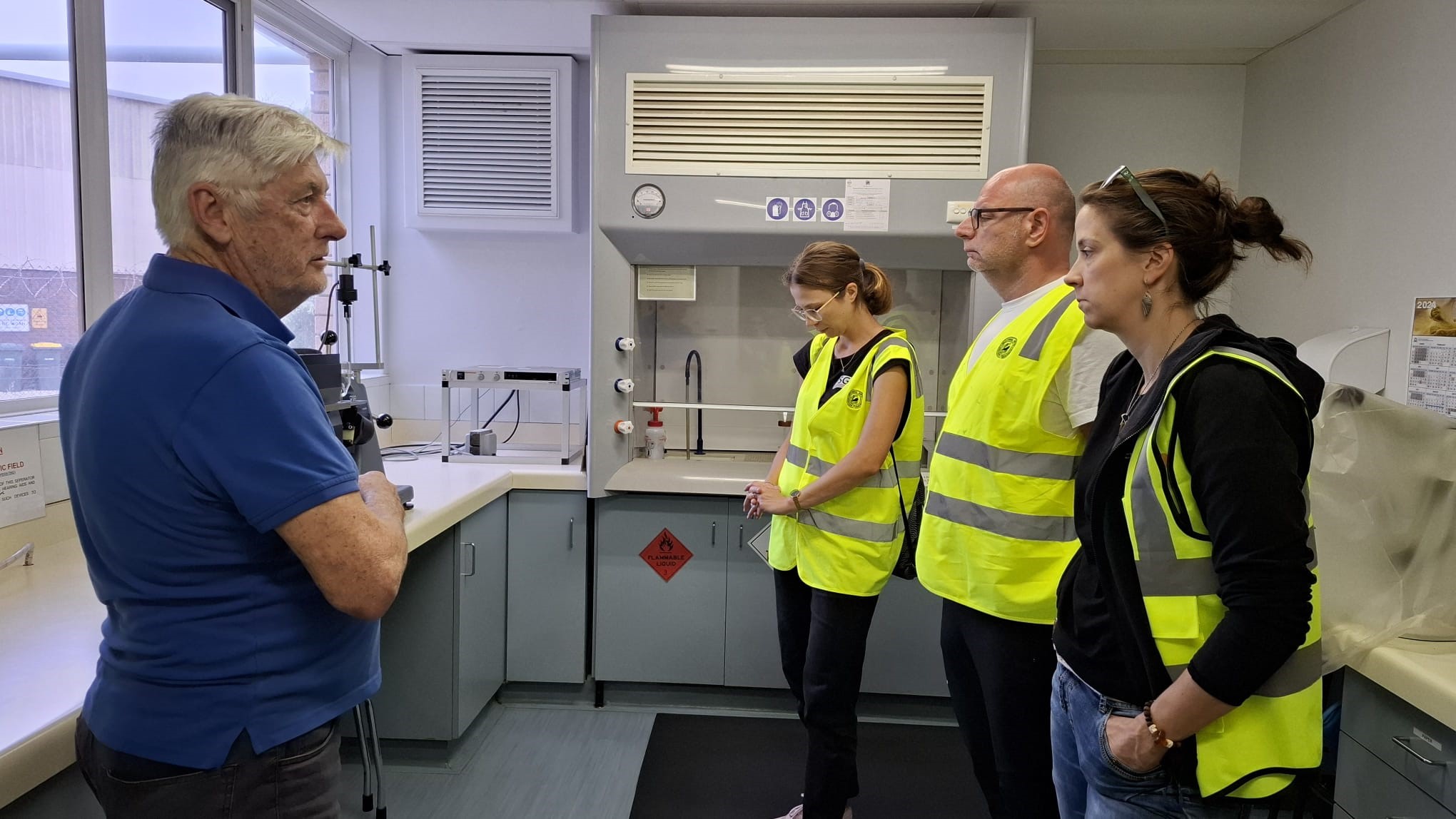 grupa ludzi w laboratorium rozmawia ze sobą