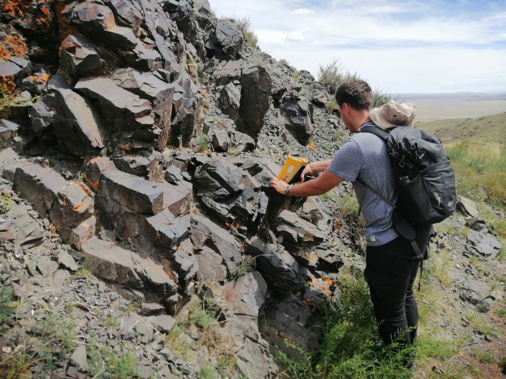 mężczyzna wykonuje badania geologiczne i chemiczne na skale w terenie