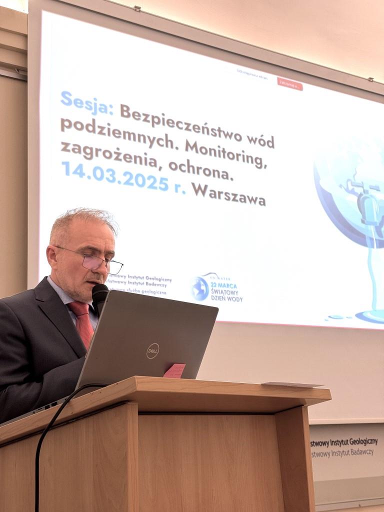 mężczyzna przemawia na tle ekranu z prezentacją