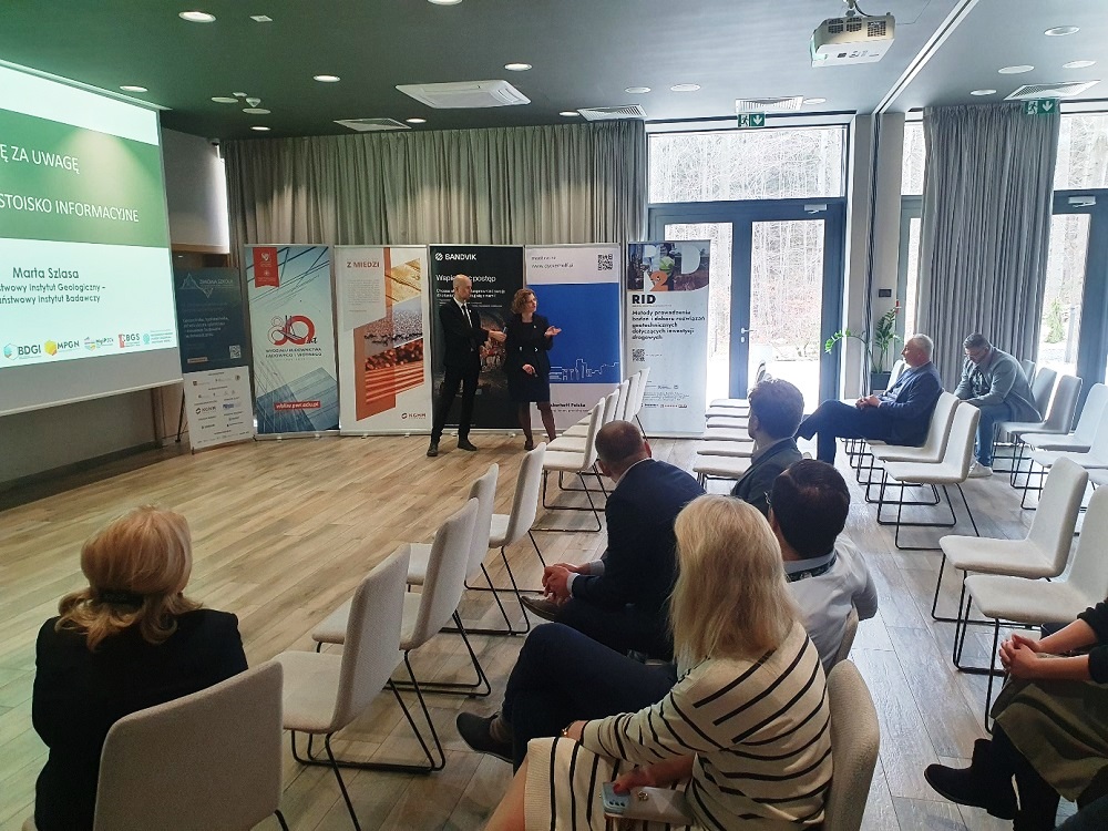 dwie osoby prezentują referat w sali