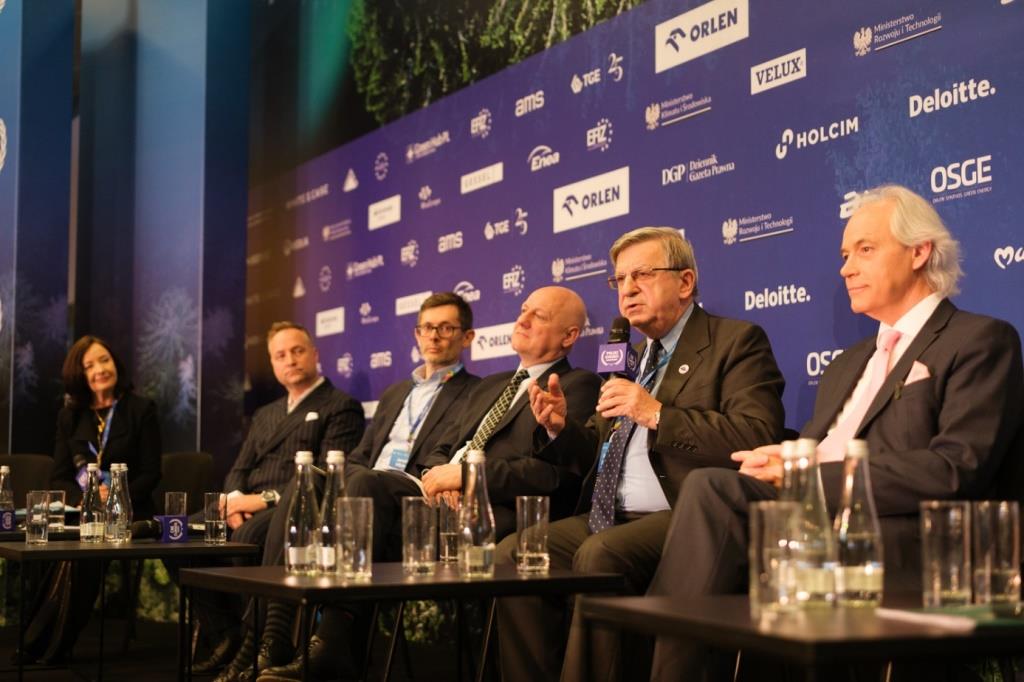 kilku mężczyzn w garniturach bierze udział w dyskusji panelowej w dużej skali