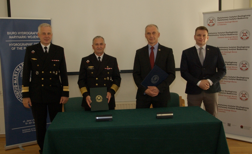 czterech mężczyzn w garniturach i mundurach pozuje do zdjęcia w eleganckim pomieszczeniu