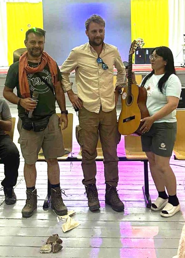 dwóch mężczyzn i kobieta pozują do zdjęcia z gitarą
