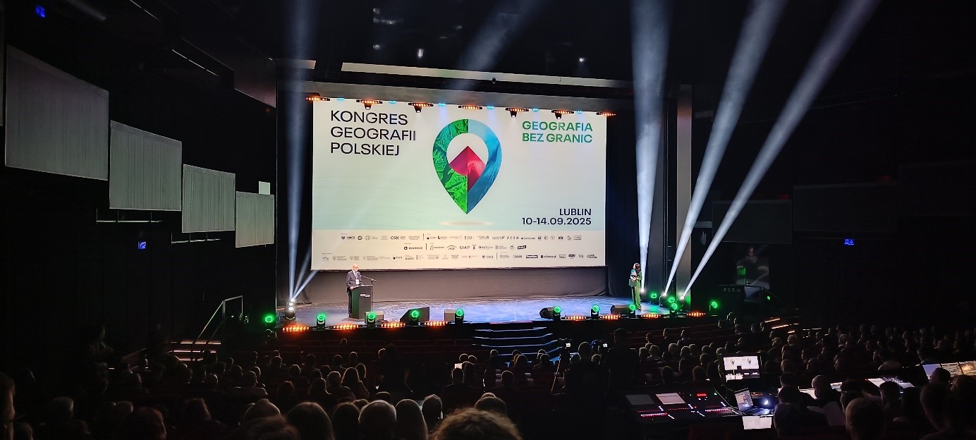 mężczyzna z mikrofonem w ręce podczas prelekcji, na tle ekranu