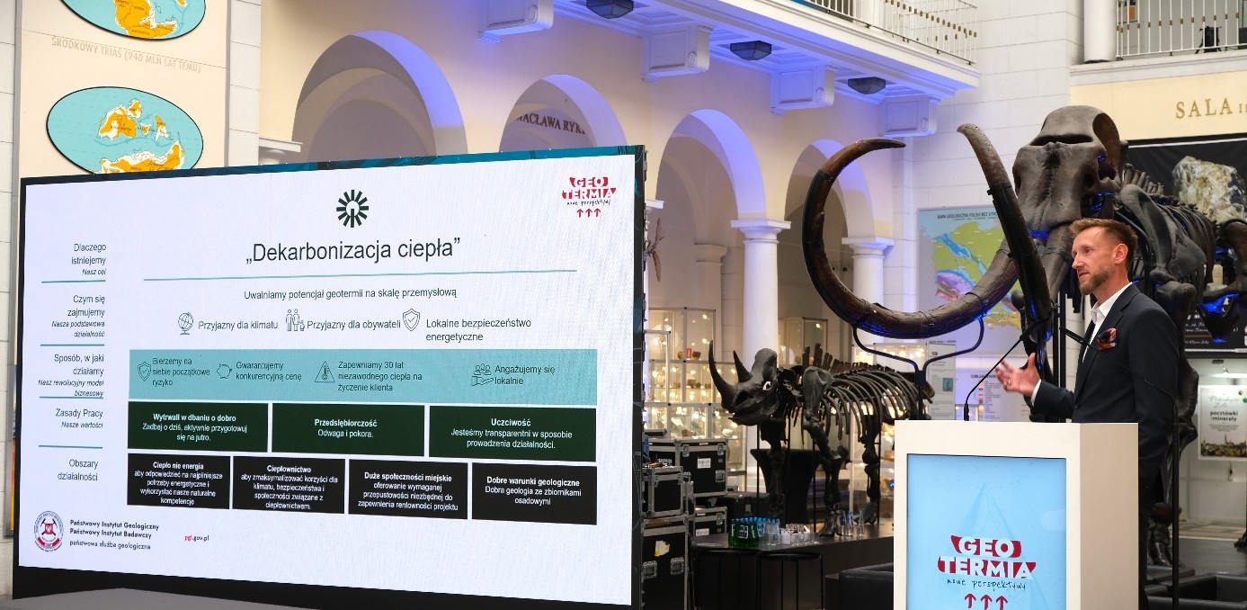 mężczyzna z mikrofonem w ręce podczas prelekcji, na tle ekranu