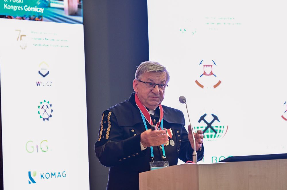 mężczyzna przemawia do siedzącej w pomieszczeniu publiczności