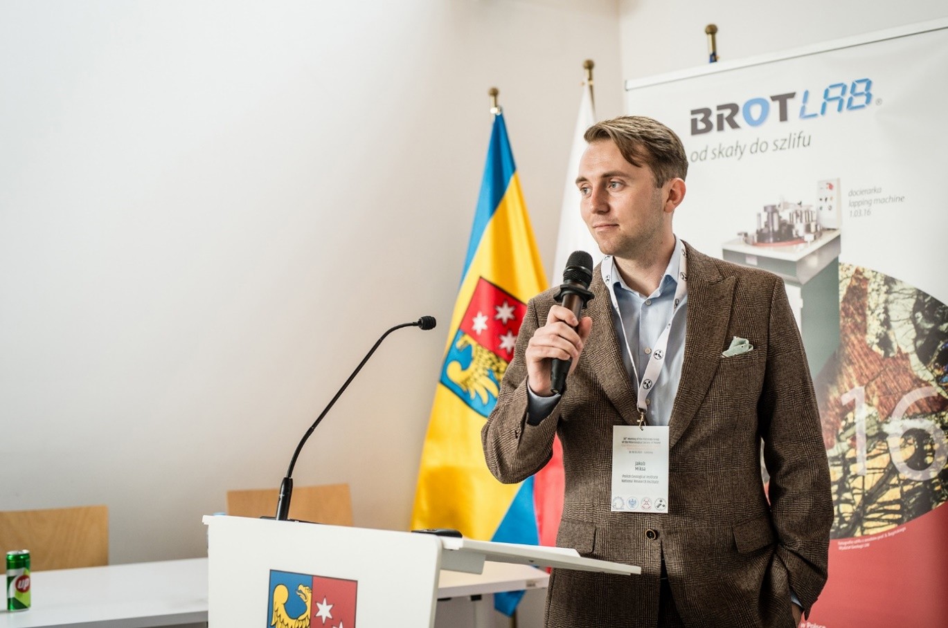 mężczyzna z mikrofonem w ręce podczas prelekcji, na tle ekranu