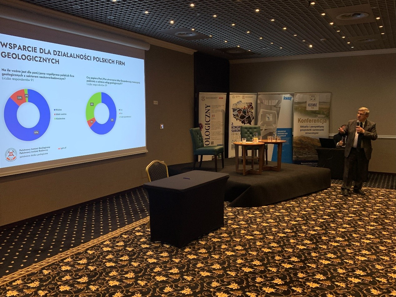 mężczyzna z mikrofonem w ręce podczas prelekcji, na tle ekranu