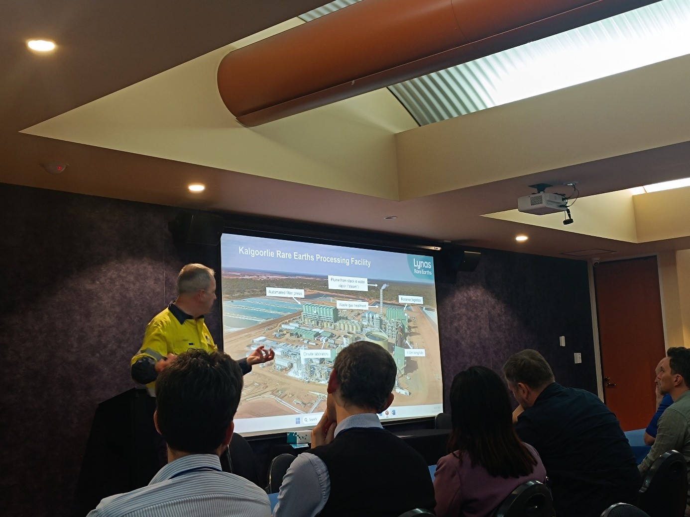 mężczyzna z mikrofonem w ręce podczas prelekcji, na tle ekranu