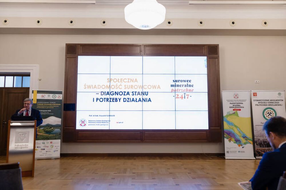 mężczyzna przemawia do siedzącej w pomieszczeniu publiczności