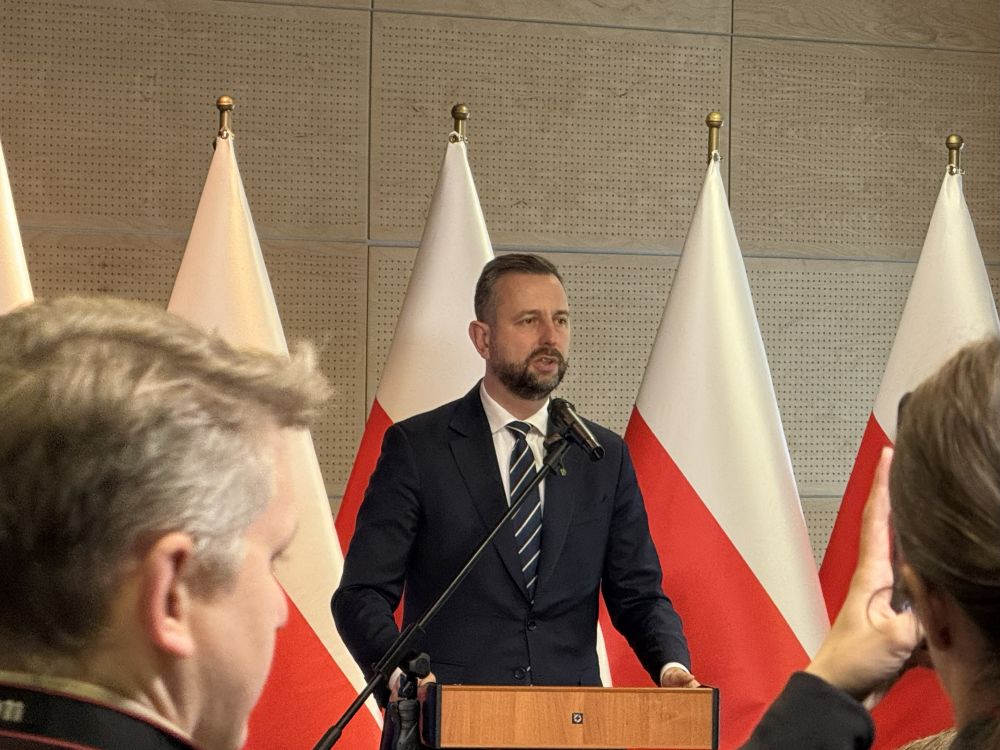 mężczyzna przemawia do siedzącej w pomieszczeniu publiczności