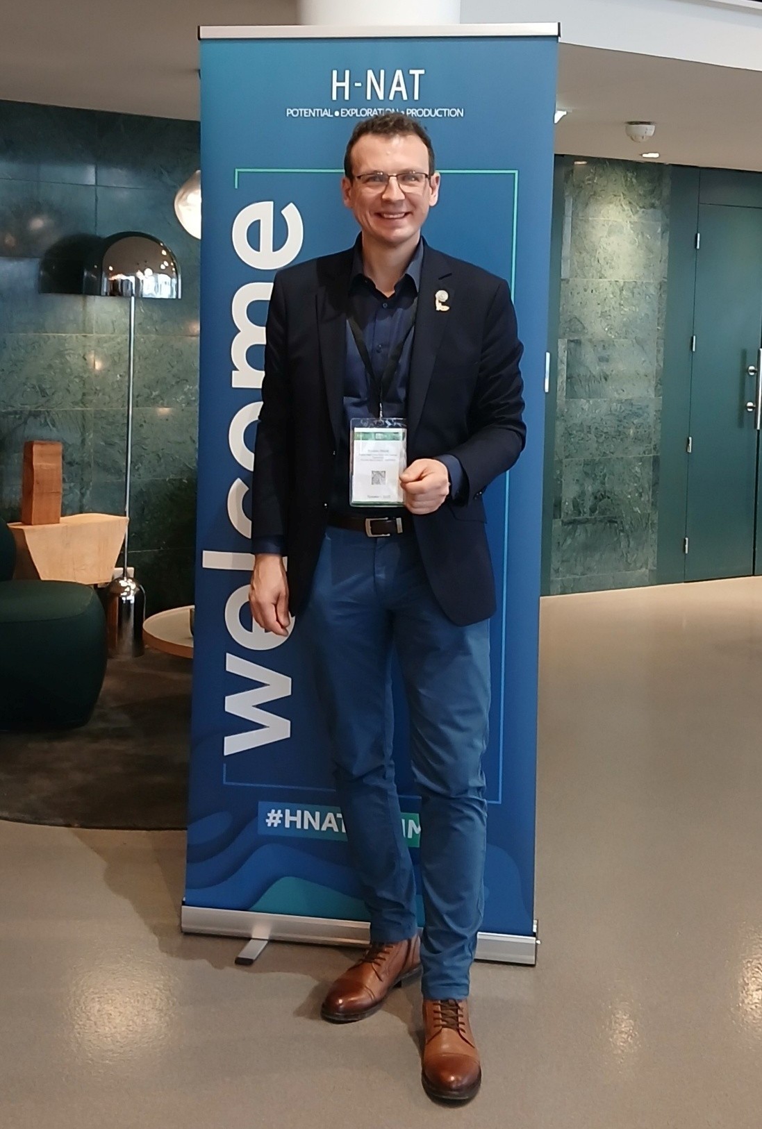 mężczyzna pozuje do zdjęcia na tle baneru promocyjnego