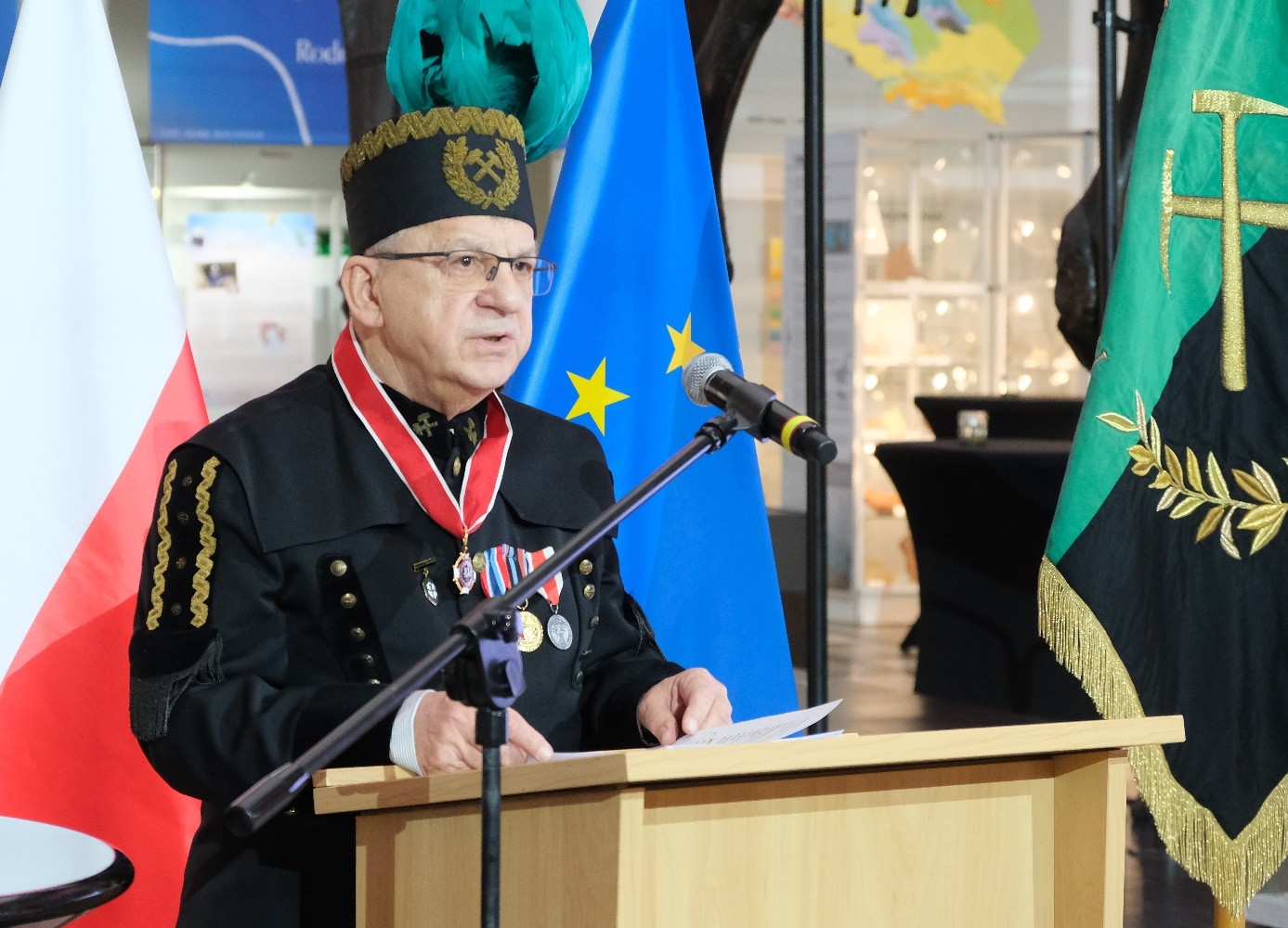 mężczyzna przemawia do siedzącej w pomieszczeniu publiczności