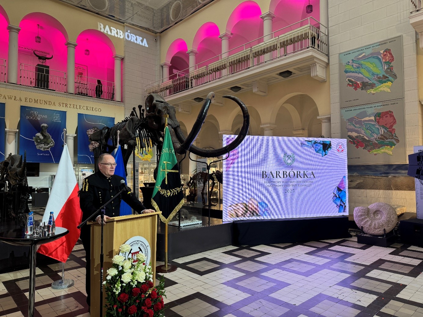 mężczyzna przemawia do siedzącej w pomieszczeniu publiczności