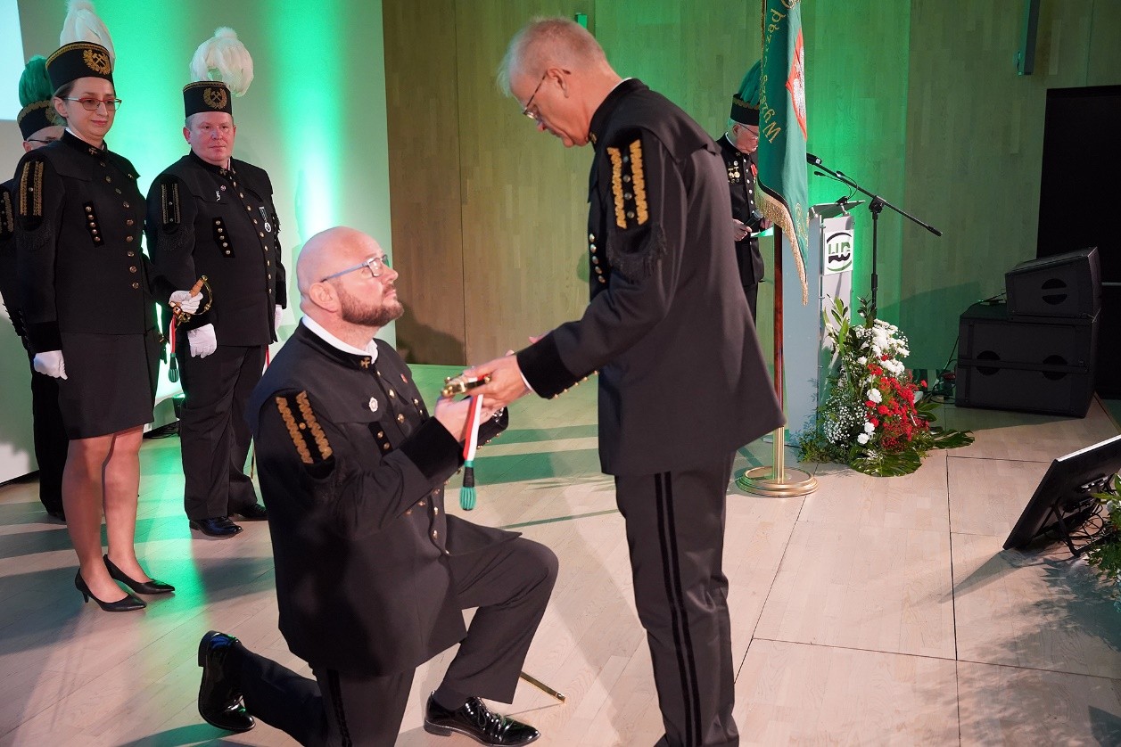 mężczyzna w mundurze górniczym klęczy na ziemi