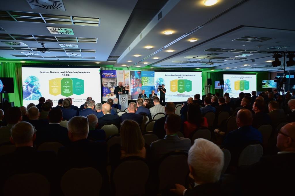 sala konferencji podczas prezentacji, ekran z prezentacją, mównica i mówca oraz audytorium na sali, wsłuchane w słowa przemawiającego