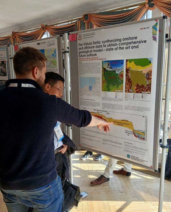 mężczyzna wskazuje dłonią na poster