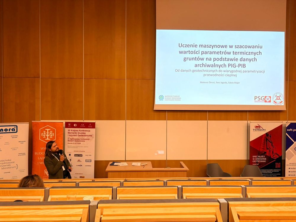 mężczyzna z mikrofonem w ręce podczas prelekcji, na tle ekranu