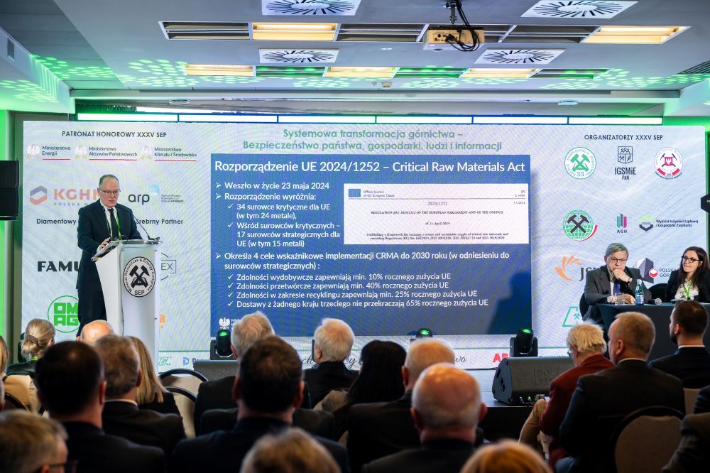 mężczyzna przemawia do siedzącej w pomieszczeniu publiczności