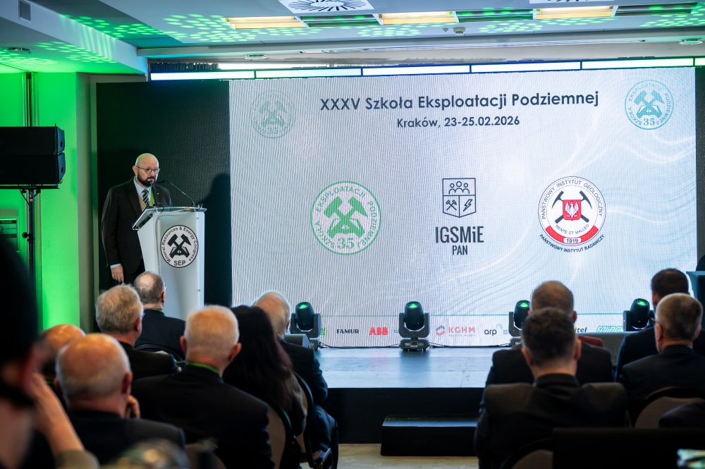 mężczyzna z mikrofonem w ręce podczas prelekcji, na tle ekranu