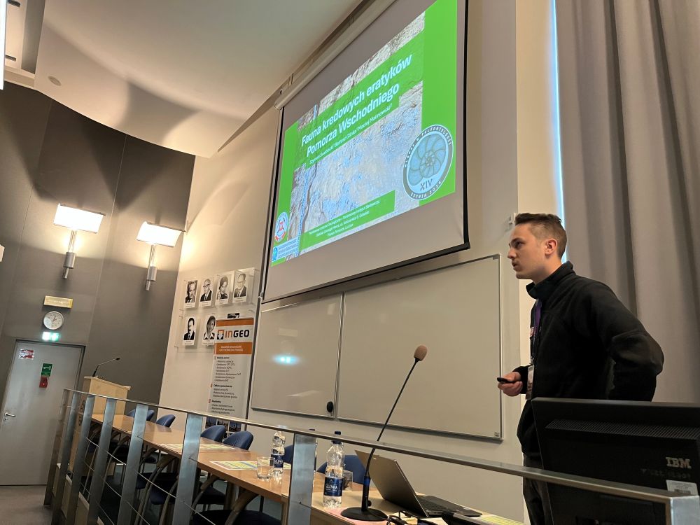 mężczyzna przemawia do siedzącej w pomieszczeniu publiczności