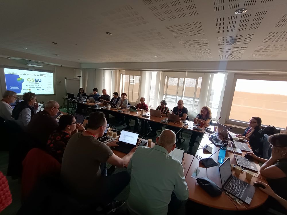 grupa osób siedząca na sali przy stole i prowadzących rozmowę ze sobą