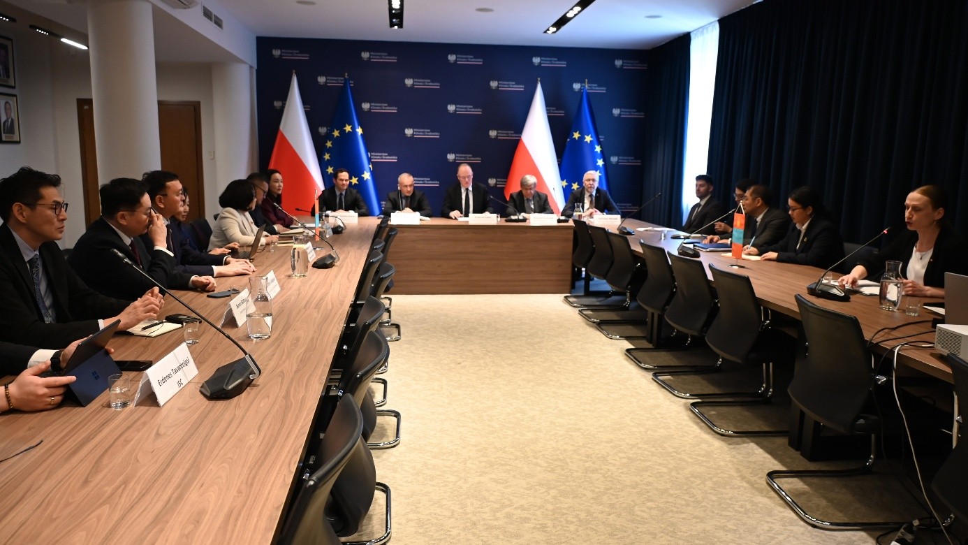 grupa osób siedząca na sali przy stole i prowadzących rozmowę ze sobą