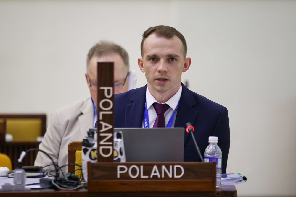 mężczyzna przemawia do siedzącej w pomieszczeniu publiczności