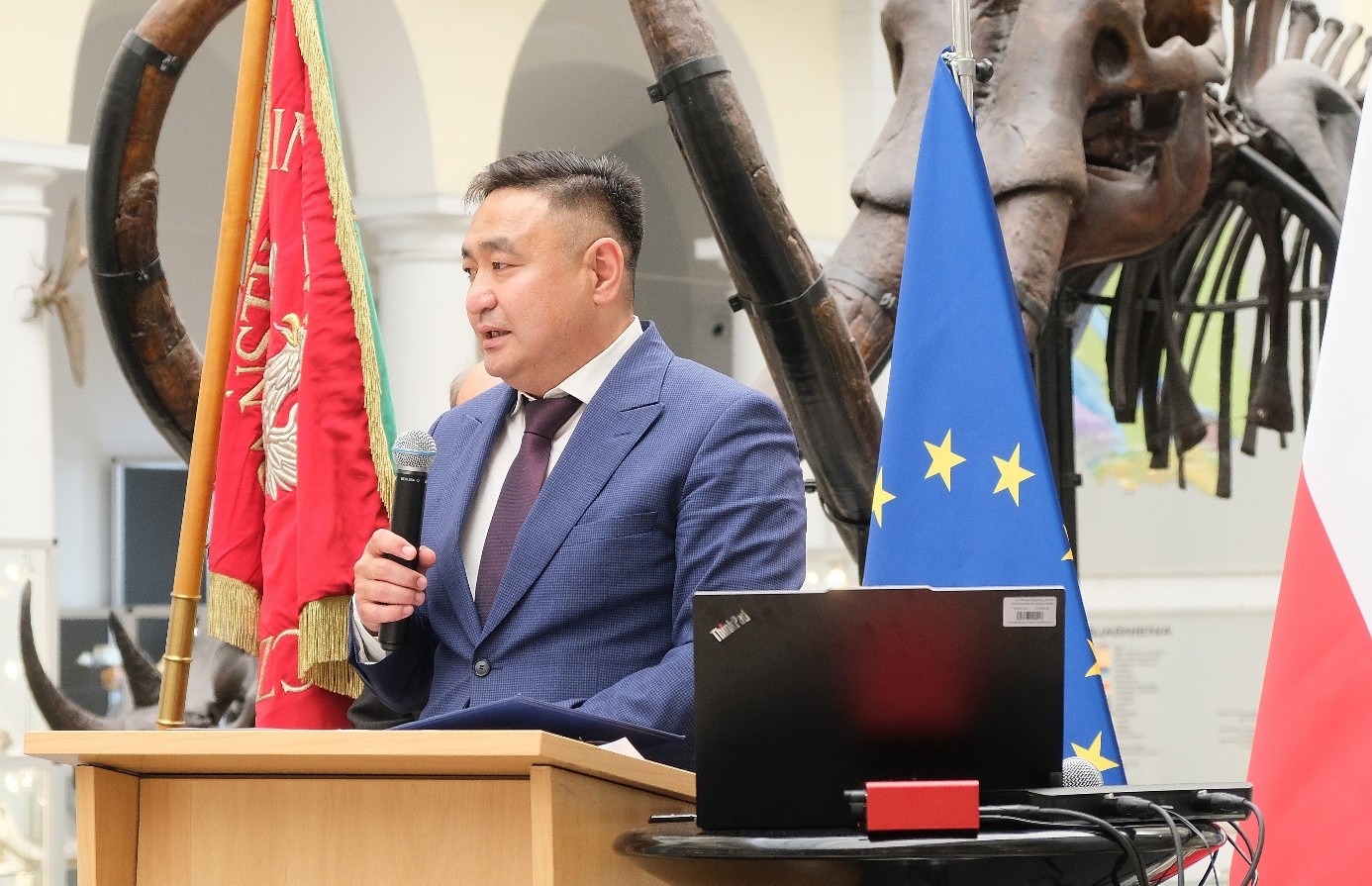 mężczyzna z mikrofonem w ręce podczas prelekcji, na tle ekranu